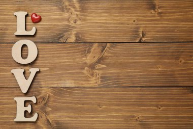 Aşk kelimesi harf ve kırmızı kalpten yapılmıştır. Tahta masada, düz bir şekilde. Metin için boşluk