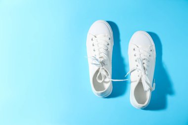 Açık mavi arka planda bir çift şık spor ayakkabı, üst manzara. Metin için boşluk
