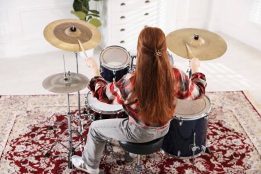 Bagetli genç kız davul çalmayı içeride, arka planda öğreniyor.