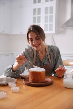Genç bir kadın geleneksel paskalya pastasını mutfakta jöleli dekore ediyor.