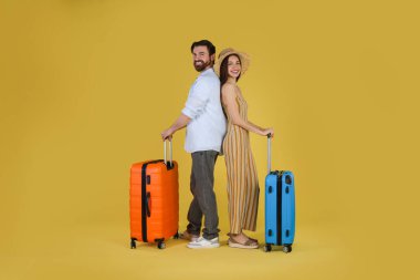 Sarı arka planda bavulları olan mutlu çift.