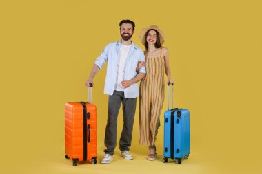 Sarı arka planda bavulları olan mutlu çift.