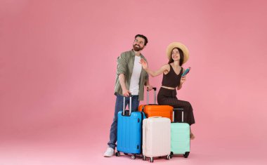 Bavullu mutlu çift, pasaport ve pembe arka planda biletler, mesaj için yer