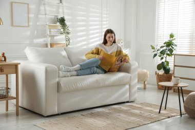 Dergisi olan kadın evdeki kanepede dinleniyor.