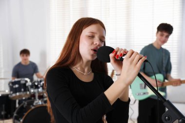 Genç müzik grubu içeride performanslarını prova ediyor.