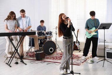 Gençlik bandosu içeride müzik öğretmeniyle performans çalışması yapıyor.