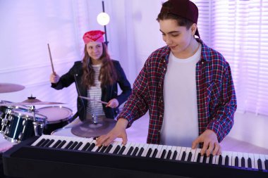 Genç müzik grubu içeride performanslarını prova ediyor.