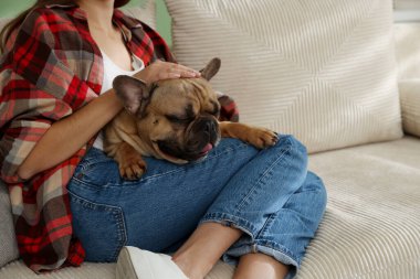 Şirin köpeğiyle evdeki kanepede dinlenen bir kadın.