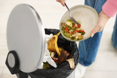 Mutfaktaki çöp tenekesine yemek atan kadın, yakın plan.