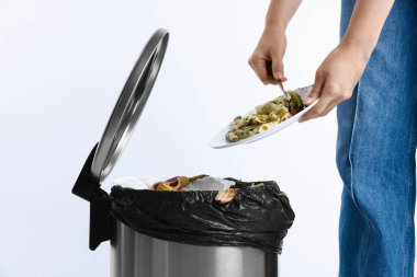 Beyaz arka planda çöp tenekesine yemek atan kadın, yakın plan.