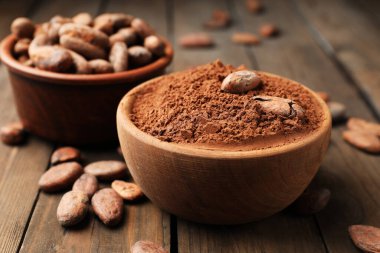 Doğal kakao çekirdeği ve toz tahta masanın üzerinde, yakın plan.
