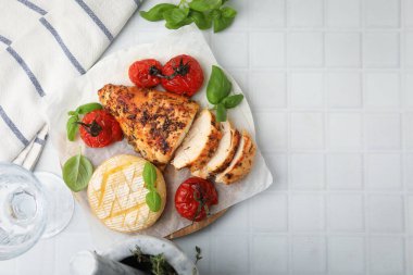 Lezzetli kızarmış tavuk göğsü, peynir, güneşte kurutulmuş domates ve fesleğen, beyaz fayanslı masa, düz yatak. Metin için boşluk