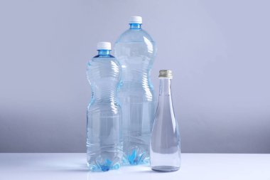 Beyaz masada gri arka planda farklı boyutlarda su şişeleri