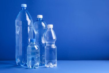Mavi arka planda farklı boyutlarda su şişeleri var. Metin için boşluk