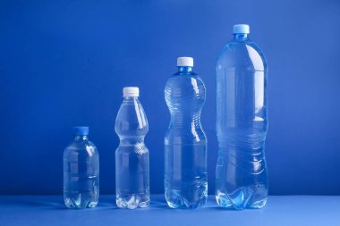 Mavi arka planda farklı boyutlarda su şişeleri