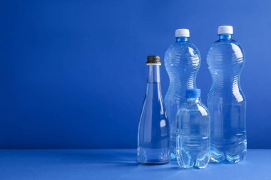 Mavi arka planda farklı boyutlarda su şişeleri var. Metin için boşluk