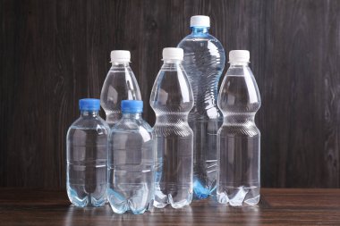 Tahta masada farklı boyutlarda su şişeleri var.