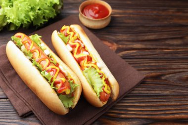 Ahşap masada soslu ve marullu lezzetli sosisliler, yakın plan. Metin için boşluk