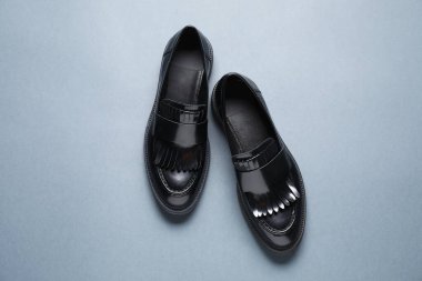 Gri arka planda bir çift şık siyah mokasen ayakkabı.