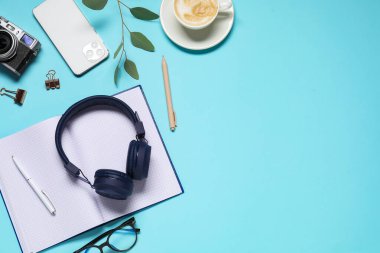 Kulaklık, akıllı telefon, klasik kamera, kahve, bardak ve kırtasiye malzemesi açık mavi arka planda, düz konum. Metin için boşluk