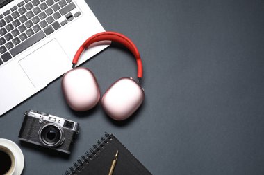Kulaklıklar, klasik kamera, kahve, kırtasiye malzemesi ve siyah arka planda dizüstü bilgisayar, düz yatak. Metin için boşluk