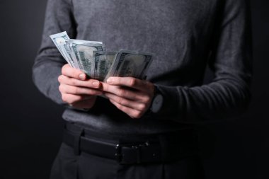 Koyu arka planda dolar banknotları olan iş adamı, yakın plan.