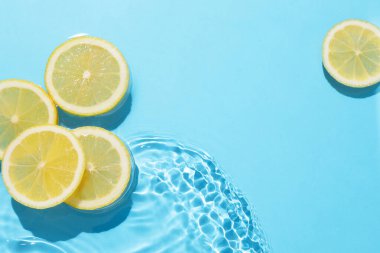 Açık mavi arka planda limon dilimleri, düz. Metin için boşluk