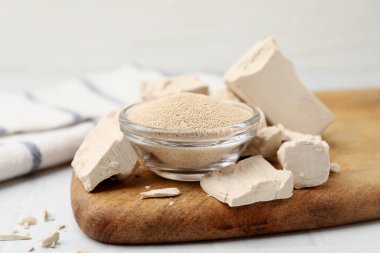 Beyaz fayanslı masada taze ve kuru maya, yakın plan.