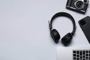 Kulaklıklar, akıllı telefon, klasik kamera ve açık gri arka planda dizüstü bilgisayar, düz konum. Metin için boşluk