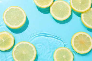 Açık mavi arka planda limon dilimleri, düz. Metin için boşluk