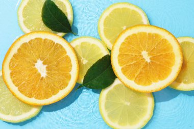 Açık mavi arka planda, sudaki yeşil yapraklar ve turunçgiller düzdü.