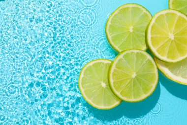 Açık mavi arka planda limon ve limon dilimleri, düz. Metin için boşluk