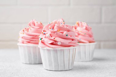 Açık gri masaya serpiştirilmiş lezzetli kekler, yakın plan.