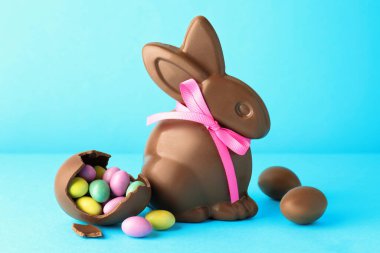 Çikolatalı Paskalya tavşanı ve açık mavi arka planda şekerli yumurta.