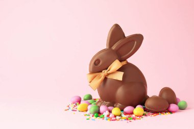 Çikolatalı Paskalya tavşanı, yumurtalar, şekerler ve pembe arka plana serpiştirilmiş şekerler. Metin için boşluk