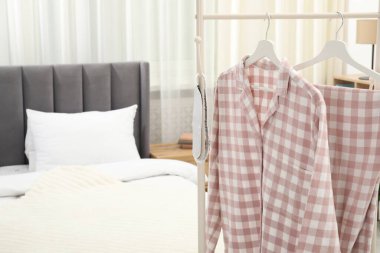 Şık pijamalar ve uyku maskesi yatağın yanındaki rafta asılı, yakın plan.