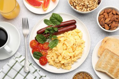 Lezzetli bir kahvaltı. Lezzetli çırpılmış yumurta, sosis ve domatesle servis edilen gri desenli masa, düz.