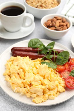 Lezzetli bir kahvaltı. Lezzetli çırpılmış yumurta, sosis ve domatesler gri desenli masa, yakın plan.