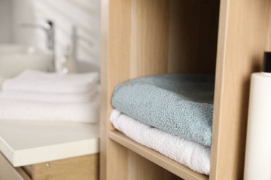 Banyodaki rafların ahşap raflarında yumuşak havlular, yakın çekim.