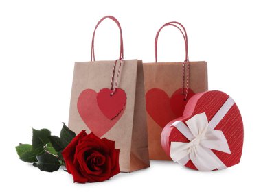 İçinde kalp şeklinde hediye kutusu olan kağıt torbalar ve beyaz üzerine izole edilmiş gül. Sevgililer Günü