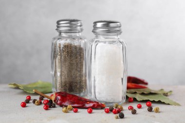 Açık gri masada baharatlı tuzluk ve biberlikler, yakın plan.