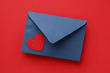 Sevgililer Günün kutlu olsun. Tebrik kartı ve kırmızı arka planda dekoratif kalp ile zarf, üst görünüm