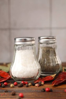 Ahşap masada baharatlı tuzluk ve biberlikler, yakın plan.