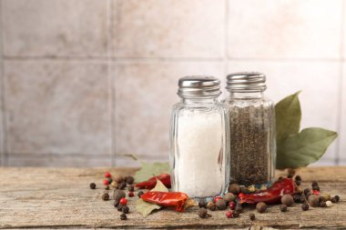 Ahşap masada baharatlı tuzluklar ve biberlikler bulanık arka planda, yakın plan. Metin için boşluk