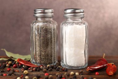 Ahşap masada baharatlı tuzluklar ve biberlikler bulanık arka planda, yakın plan