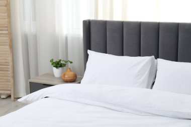 Yatak odasında temiz beyaz çarşafları olan rahat bir yatak.