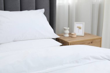 Yatak odasında temiz beyaz çarşafları olan rahat bir yatak, yakın plan.