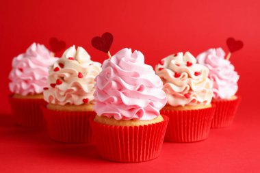 Sevgililer Günün kutlu olsun. Kırmızı arka planda kalpleri olan lezzetli kekler, yakın plan.