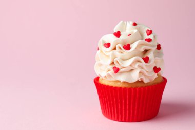 Sevgililer Günün kutlu olsun. Pembe arka planda kırmızı kalpleri olan lezzetli kek, yakın plan. Metin için boşluk