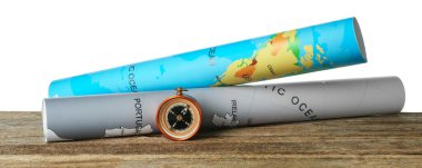 Yolculuk. Pusula ve dünya haritaları beyaz arkaplana karşı ahşap masa üzerinde